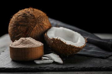Wooden bowl with coconut flour and fresh nuts on table