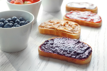 Slices of bread with jam and peanut butter on light background
