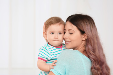 Young mother with baby on light background