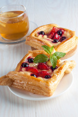 Fresh fruit tart with berries jam decorated with cranberry, mint on wooden rustic background wit a cup of tea. Desert. Morning healthy breakfast and evening dinner.