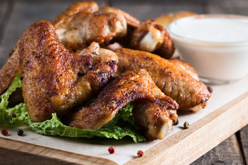Close-up photo of bbq chicken wings with fries and beer. Barbeques meat with sauces, ketchup, mayonnaise. Fast and junk food concept. 