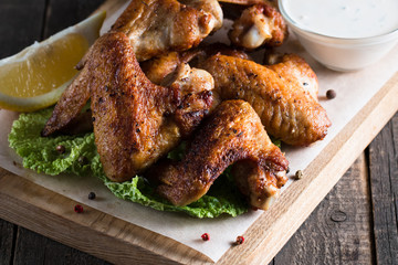 Close-up photo of bbq chicken wings with fries and beer. Barbeques meat with sauces, ketchup, mayonnaise. Fast and junk food concept. 