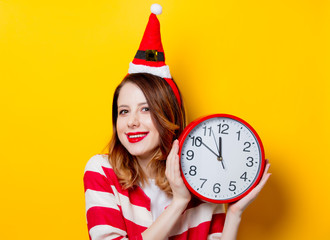 Smiling woman in Santa Claus hat with clock