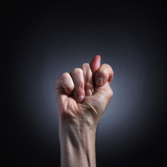 The human hand in a gesture of blowing closeup on dark background.