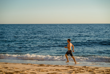 Man running on the beach at sunset