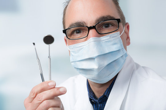 Zahnarzt hält zwei Zahnarztinstrumente in der Hand