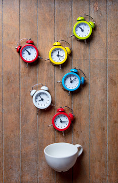 cup with alarm clocks on wooden background