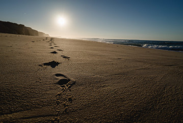 Footsteps on the beach in Portugal at sunset