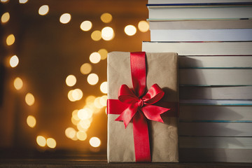 Christmas gift box and pile of books with fairy lights