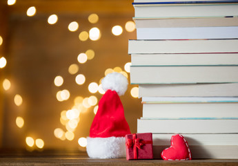 Fototapeta premium gift box, Santa Claus hat and pile of books