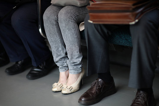 Legs of a woman in jeans, sitting in a subway car among men