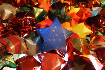 blauer Stern inmitten vieler anderer bunter Papiersterne f&uuml;r Weihnachten