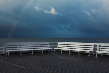 Place for rest and meditation concept. Beautiful view from white wooden pier on calm sea with rainbow. Stormy weather. Text-space. Sopot, Poland. Outdoor shot