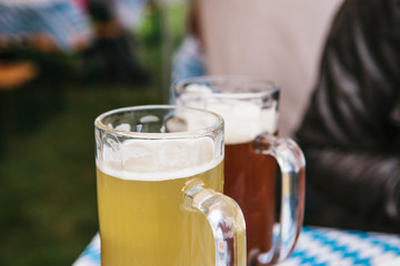Two mugs with a light and dark beer stand on the table. Celebrating the traditional German beer festival called Oktoberfest