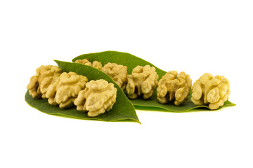 light yellow walnut core close-up with peel and leaves stacked in a isolate composition on a white background