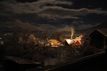 Christmas fairy tale. Winter night. Smoking chimney of house in mountain village. Nature and travel. Russia, Adygea, Caucasus Mountains