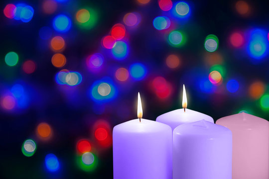 Christmas violet and pink candles. Second Sunday of the Advent. Bethlehem, Peace Candle. Xmas concept on a bokeh background.