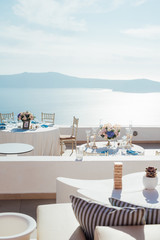 Vertical photography of place for a wedding dinner on the island of Santorini with white tables with decor and sea view