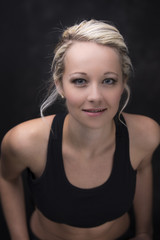 Beautiful fit and healthy blond woman portrait in black top in dark with selective lighting