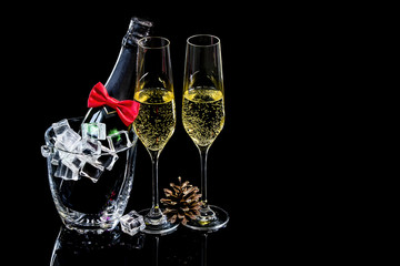 Bottle of champagne in ice bucket with wineglasses and pine cone