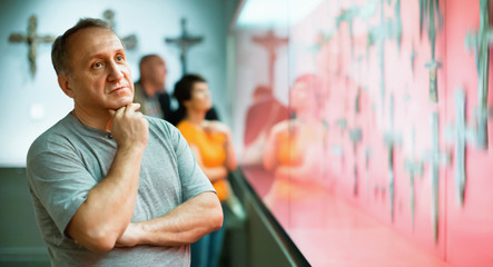 Portrait of thoughtful elderly man examining exposition in museu