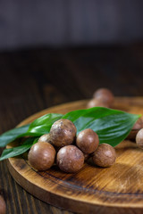 Fresh and ripe macadamiya nuts on the wooden board.