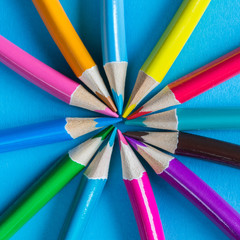Fototapeta premium Multicolored pencils on a blue background with a large frame