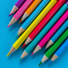Multicolored pencils on a blue background with a large frame