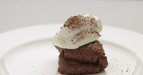 Serving soft chocolate mousse with whipped cream and cocoa powder on white plate