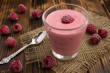 Yogurt with frozen raspberries on the rustic wooden background