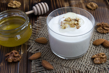 Milk yogurt with honey and nuts on the rustic wooden background