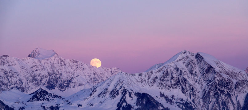 full moon rising in winter in the Swiss Alps over mountains near Klosters in the Raetikon mountain range