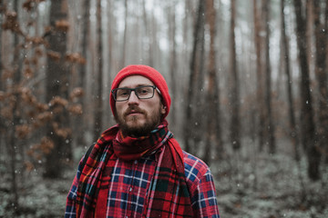 a man with a beard in a red cap reacts emotionally in the forest