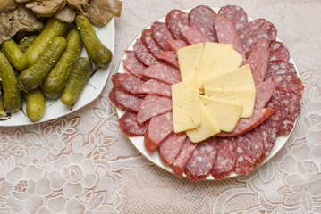 Sausage, cheese, mushrooms and cucumbers on a dish.