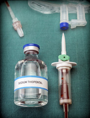 Rubber drip irrigation system with traces of blood along with vial of sodium thiopental, conceptual image