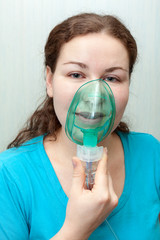 Catch cold woman with sore throat making inhalation itself with a mask on her face. Nebulizer device