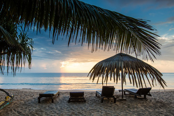 Sun loungers with umbrella on the beach, sunrise