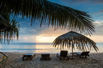 Fototapeta na wymiar Sun loungers with umbrella on the beach, sunrise
