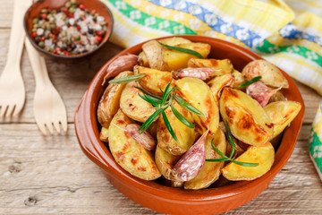Potato wedges baked with garlic, rosemary and spices in a ceramic form. Selective focus