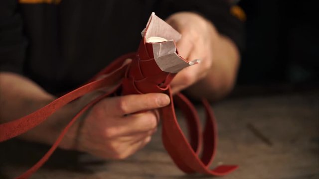 Working proccess of leatherworker covering plastic tube with red leather stripes. He works very carefully and accurately.