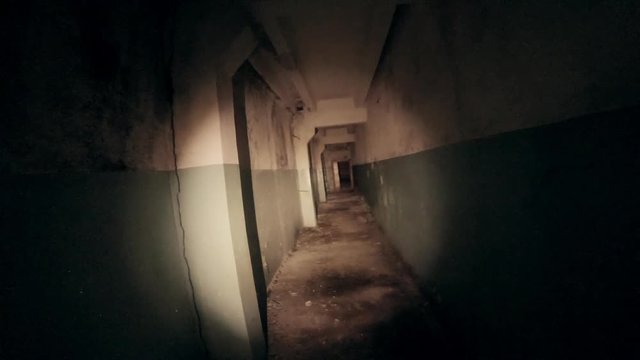 Moving through dark creepy corridor. First person view, going with flashlight in dirty grungy tunnel in abandoned building, horror escape concept, toned