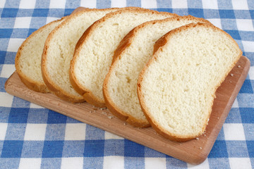 Sliced wheat bread on the wooden plate on tablecloth