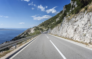 Asphalt road to the sea. Asphalt highway in a sunny day.