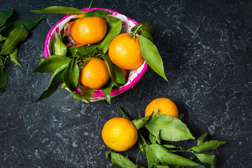 Fresh mandarin with leaves on darl stone background