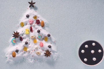 Christmas tree of sugar on a white background, decorated with sweets, nuts, spices and a cup of chocolate