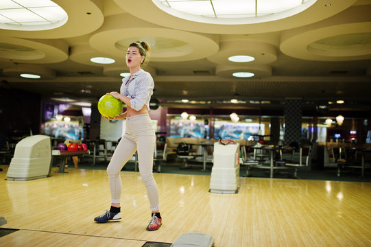Girl with bowling ball on alley played at bowling club.