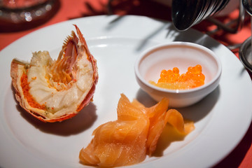 Lobster tail, salmon caviar fish roe and cold smoked salmon seafood dish served on a plate in a restaurant