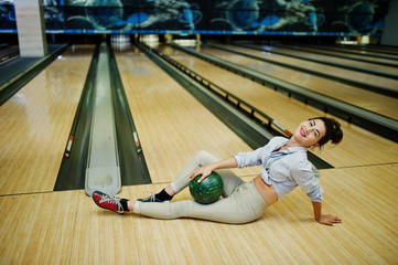 Girl with bowling ball on alley played at bowling club.