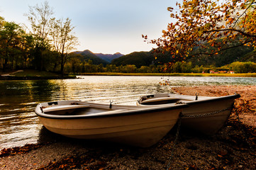 Two boats on the lake shore at sunset.
