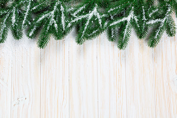 Christmas fir tree with snow on white wooden background. Free space frame